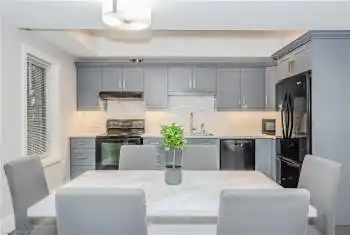 Kitchen featuring tasteful backsplash, light counters, sink, black appliances, and gray cabinets
